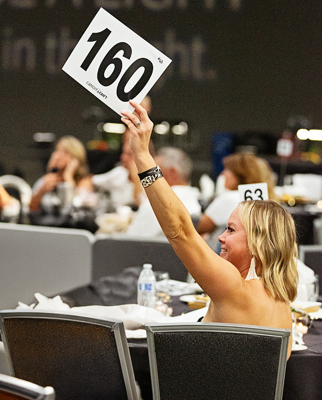 Woman bidding on an auction item at the annual Cancer Can't Gala
